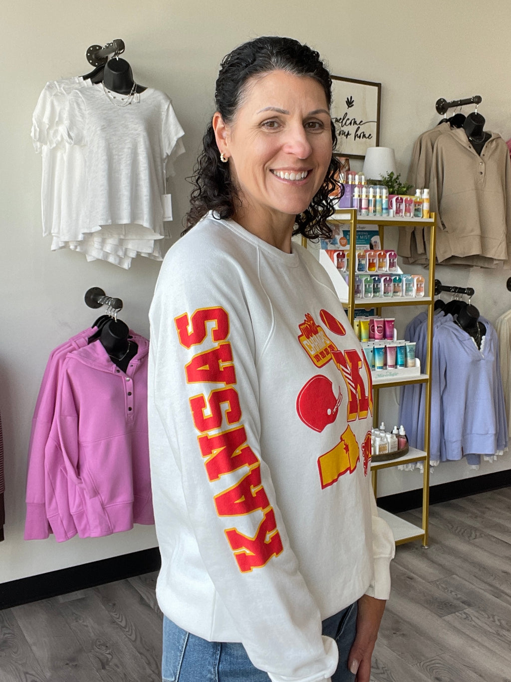 white crewneck with screen printed patches featuring KC, a football, pennant, and Kansas City down the sleeves.